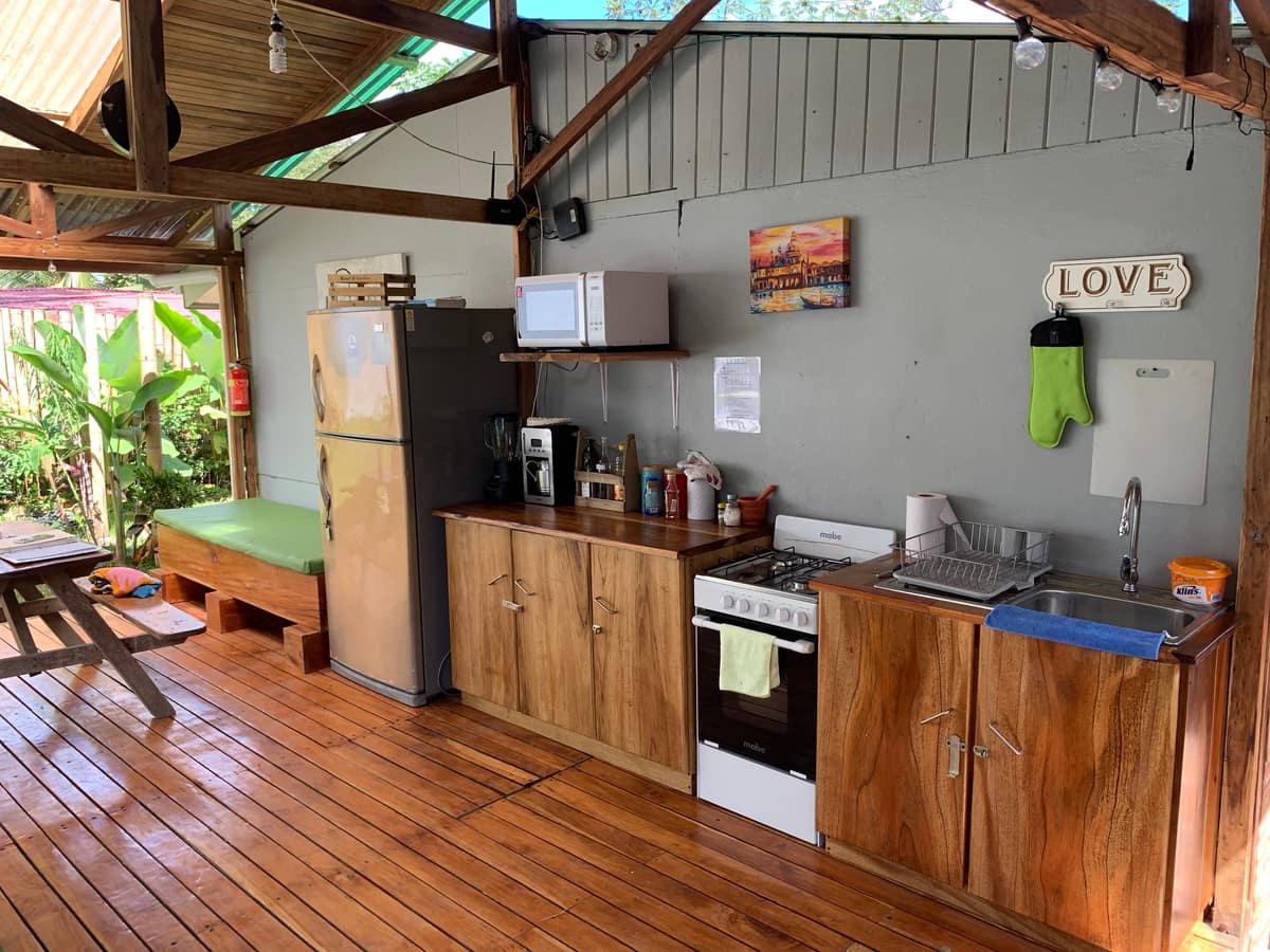 La cocina abierta para huéspedes bajo el rancho: refri, cocina de gas, microondas y coffee maker — foto real